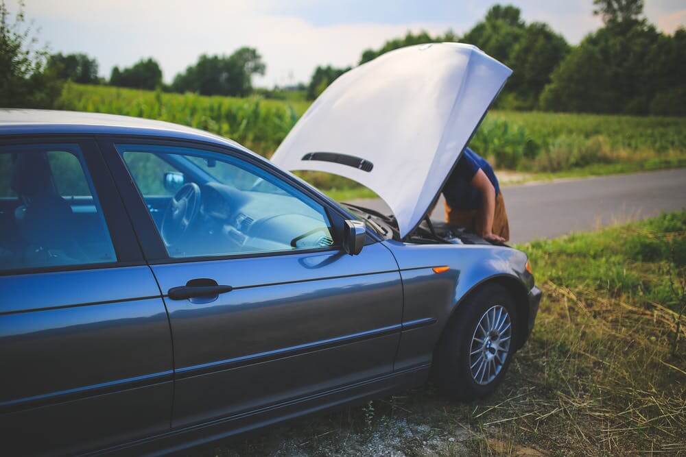 person checking beneath vehicle bonnet