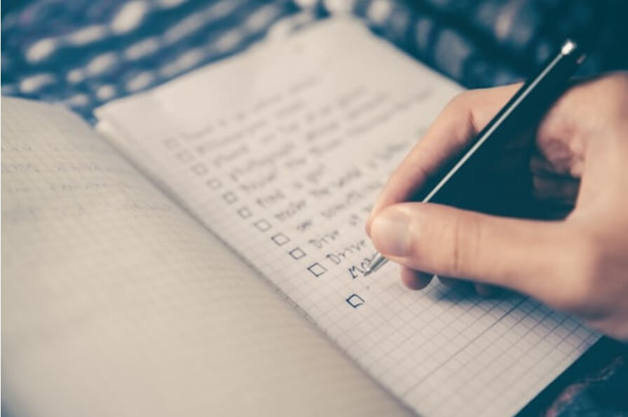 person writing in notebook to make  fleet vehicle care chekclist 