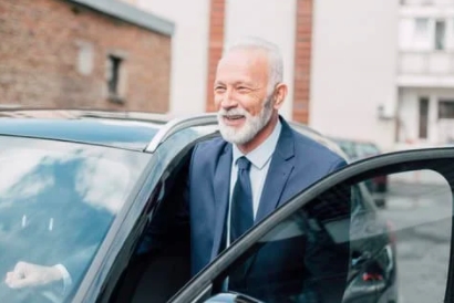 A businessman getting into a car with a Car Tracker Fitting