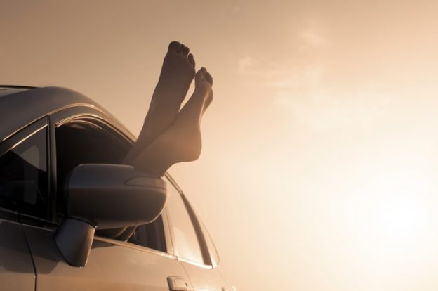 Nackte Füße werden aus dem Autofenster gehängt.